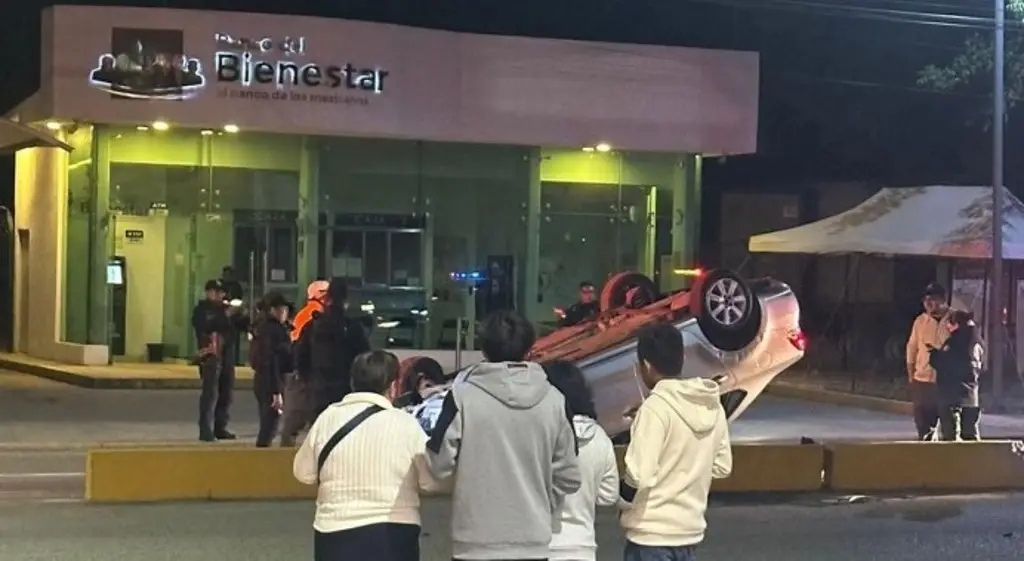 Imagen Fuerte volcadura de carro particular frente a banco del bienestar; queda 'llantas arriba'