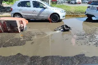 Caen con todo y moto a socavón en entrada a central de abastos; piden reparar calle